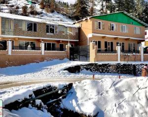 a house with snow in front of it at Shail Shikhar Heritage Inn in Joshīmath