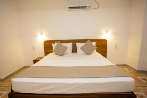 a bedroom with a bed with white sheets and pillows at Lucky Seven Hikkaduwa in Hikkaduwa
