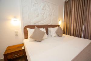 a bedroom with a bed with white sheets and pillows at Lucky Seven Hikkaduwa in Hikkaduwa