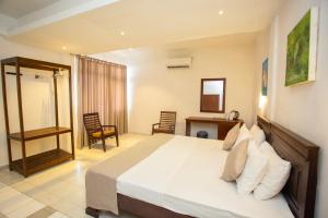 a bedroom with a bed and a desk and chairs at Lucky Seven Hikkaduwa in Hikkaduwa
