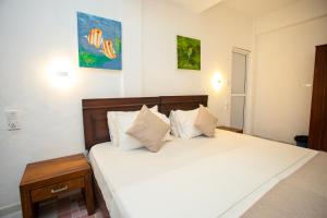 a bedroom with a bed with white sheets and pillows at Lucky Seven Hikkaduwa in Hikkaduwa