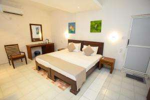 a bedroom with a bed and a desk and a chair at Lucky Seven Hikkaduwa in Hikkaduwa