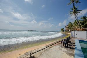 a bench sitting on the beach near the ocean at Lucky Seven Hikkaduwa in Hikkaduwa