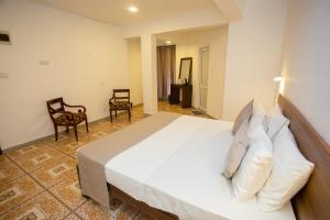 a bedroom with a large white bed and two chairs at Lucky Seven Hikkaduwa in Hikkaduwa