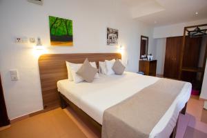 a bedroom with a large bed with white sheets and pillows at Lucky Seven Hikkaduwa in Hikkaduwa