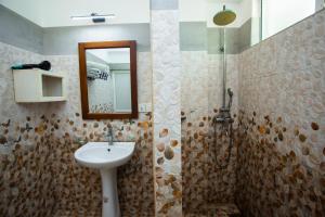 a bathroom with a sink and a mirror and a shower at Lucky Seven Hikkaduwa in Hikkaduwa
