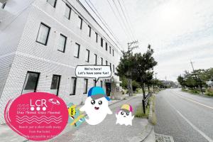 a building with signs on the side of a street at LOW COST RESORT MANZA BEACH （旧：北海荘） in Onna
