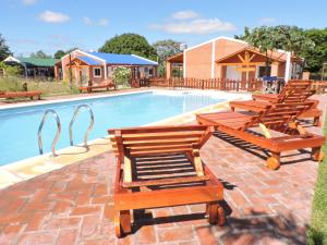 un grupo de sillas sentadas junto a una piscina en Cabañas Mburucuyá Poty en Mburucuyá