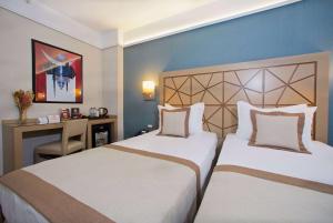a hotel room with two beds and a desk at Ramada By Wyndham İstanbul Taksim in Istanbul