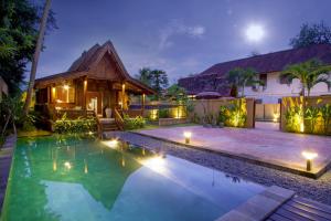 a villa with a swimming pool at night at Villa Puri Tupai in Ubud