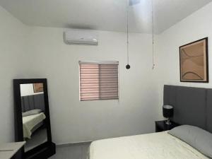 a bedroom with a bed and a mirror and a window at Departamento completo in Chihuahua