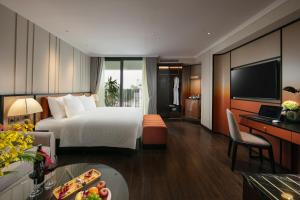 a hotel room with a bed and a desk and a television at The Chi Boutique Hotel in Hanoi