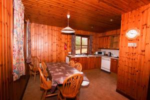 a kitchen with a table and chairs and a clock at Tullochwood Lodges in Forres