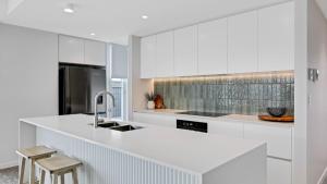 a white kitchen with a sink and a counter at Luxury Townhouse Maroochydore in Maroochydore
