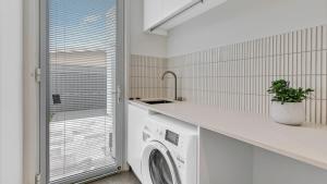 a laundry room with a washing machine and a window at Luxury Townhouse Maroochydore in Maroochydore