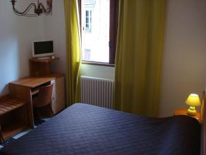 a bedroom with a bed and a desk and a window at Hôtel Restaurant Sole e Monte in Cuttoli-Corticchiato