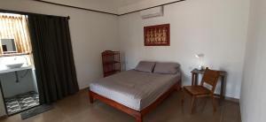 a bedroom with a bed and a chair and a window at Zen Space Nesat in Phumĭ Chroŭy Svay