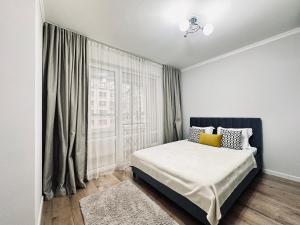 a bedroom with a bed and a large window at Ala Park apartment in Almaty