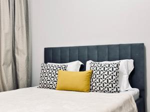 a bed with a blue headboard with a yellow pillow at Ala Park apartment in Almaty +18 photos