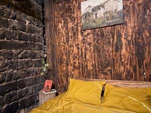 a bedroom with a yellow bed and a brick wall at Vieille Maison de Ma Lé in Mia Si