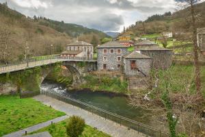 a bridge over a river next to a village at Valle del Ibias - Segundo Izquierda in Cecos