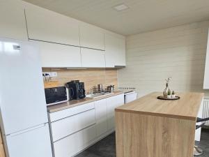 a kitchen with white cabinets and a wooden counter top at Lakeforest Dedinky Wellness Chata privát jacuzzi aj sauna, výhľad na jazero in Dedinky +9 photos