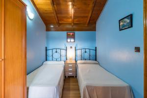 two beds in a room with blue walls at Casa Alba in Bárcena de Cicero