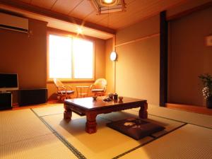 a living room with a wooden coffee table in a room at Hatoguruma Kawabata in Nozawa Onsen