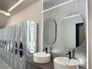 a bathroom with two sinks and two mirrors at U Capsule Hotel Kulai in Kulai