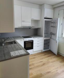 an empty kitchen with white appliances and wooden floors at Winter Moon Aparment in Rovaniemi +7 photos