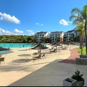 a beach with chairs and umbrellas and a pool at The Blyde lagoon Penthouse in Pretoria