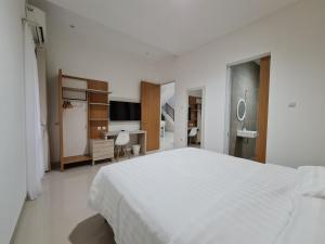 a white bedroom with a large bed and a desk at Roemah Audy in Yogyakarta