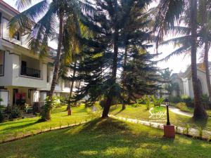 a yard with palm trees in front of a building at Susegad Suites Arpora Apartments & Villas with Reserved Parking in Arpora