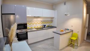 a kitchen with white cabinets and a yellow stool at Apartments on EXPO, Mega SilkWay in Astana
