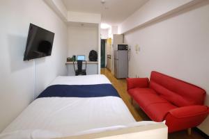 さいたま市にあるHOTEL Nishikawaguchi Weekly - Vacation STAY 43454vのベッド1台と赤いソファが備わる小さな客室です。 +5枚の写真