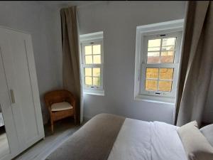 a bedroom with two windows and a bed and a chair at Esencia lagunera in Las Lagunas