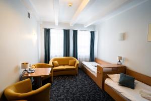 ein Hotelzimmer mit einem Bett, einem Stuhl und einem Tisch in der Unterkunft Hotel SANVIT RESTAURACJA & SPA in Sanok + 27 Fotos