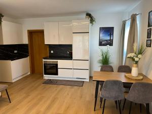 a kitchen with white cabinets and a table and chairs at Koralpen Appartement in Rieding