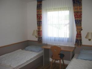 une chambre avec deux lits et un bureau et une fenêtre dans l'établissement Ferienhaus Nr 127, Kategorie Komfort L, Feriendorf Hochbergle, Allgäu, à Karlsebene