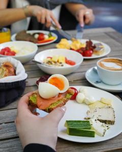 a person holding a sandwich with an egg on a table at Boston Hotel HH in Hamburg