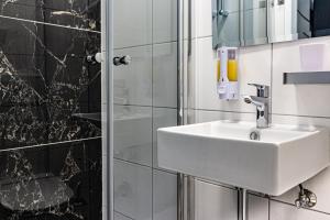 a bathroom with a white sink and a shower at Hotel Central Linz - 24h Self-Check-in in Linz +17 photos