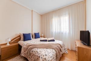 une chambre avec un lit avec des oreillers bleus et une télévision dans l'établissement MARESOL - apartment close to the beach and restaurants, à San Pedro del Pinatar