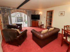 ein Wohnzimmer mit Ledermöbeln und einem Flachbild-TV in der Unterkunft Fern Cottage in Wooler