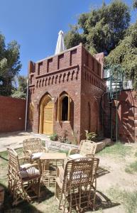 a brick building with tables and chairs in front of it at Guesthouse Nut in Luxor