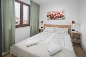 a white bedroom with a bed and a window at Apartments Špadići in Poreč