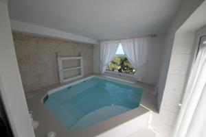 a large swimming pool in a white room with a window at Playa del Mar - Adults Only in Monopoli