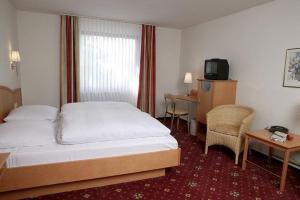 a hotel room with a bed and a tv at Klindworths Gasthof in Sauensiek
