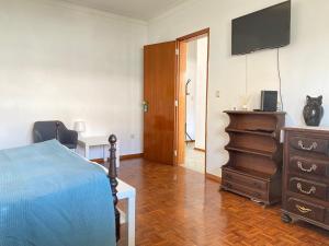 a bedroom with a bed and a dresser and a television at Refúgio Ribatejano in Alpiarça