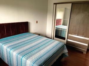 a bedroom with a bed and a closet with a mirror at Apartamento Amplo com 2 Suítes in Novo Hamburgo