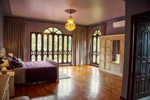 a bedroom with a bed and windows and a chandelier at Golden Goose Villas in Bedugul